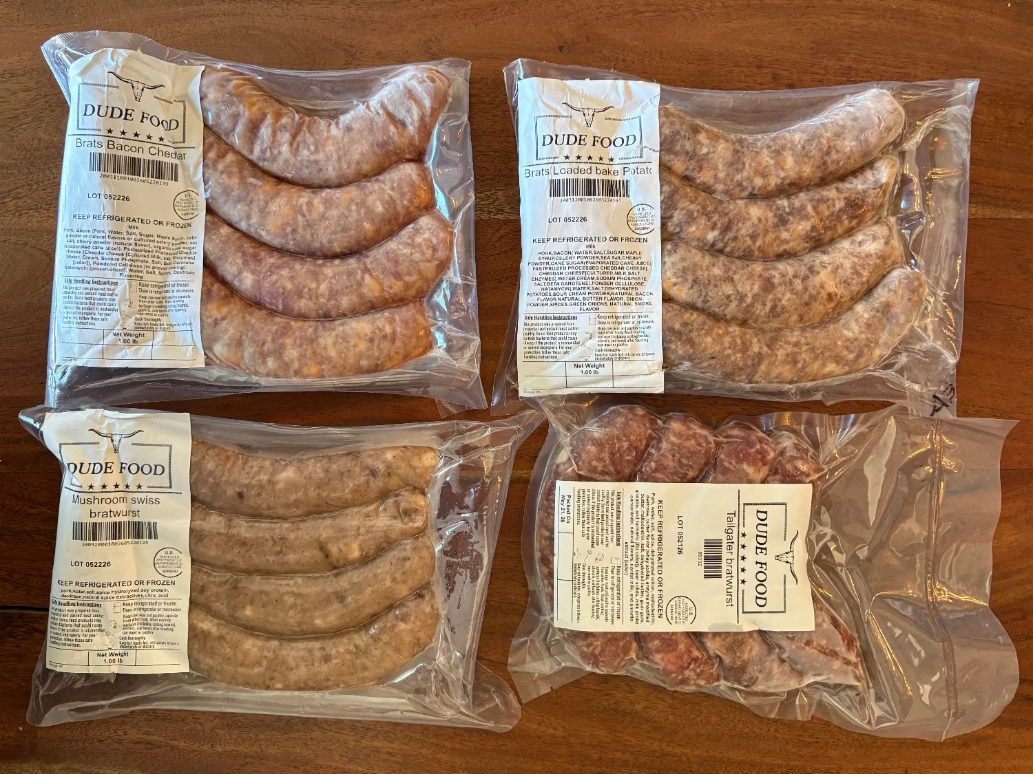 Four packages of sausages with Dude Food labels on a wooden surface
